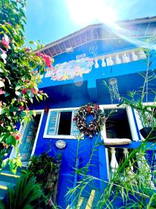 a blue house with a white door and flowers at Pousada Água Marinha-Familias & Pets in Angra dos Reis