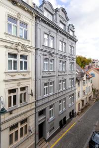 un edificio grigio con finestre bianche su una strada di Family Apartments by ASTORIA Hotel & Medical Spa a Karlovy Vary