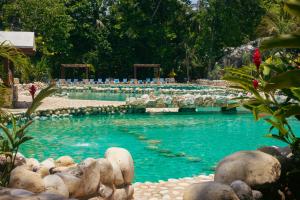 una gran piscina con sillas azules y un puente en Chan-Kah Resort Village Convention Center & Maya Spa, en Palenque