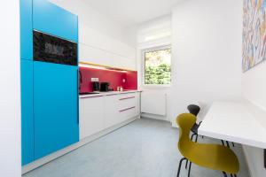 a kitchen with white cabinets and a table and yellow chairs at Family Apartments by ASTORIA Hotel & Medical Spa in Karlovy Vary