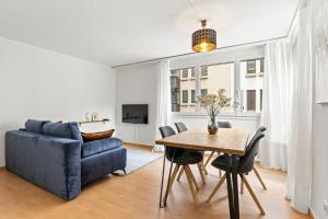 ein Wohnzimmer mit einem blauen Sofa und einem Tisch in der Unterkunft Bright, Central & Modern apartment in Luzern