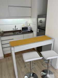cocina con encimera con microondas y 2 taburetes en Apartamento en POCITOS vista al mar en Montevideo