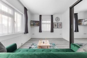a living room with a green couch and a table at Ultra Elegant 2BDR - 10 mins to stadium - Sleeps 5 in London