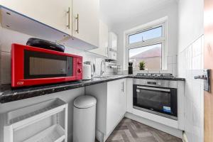 una cucina con forno a microonde rosso su un bancone di Ultra Elegant 2BDR - 10 mins to stadium - Sleeps 5 a Londra