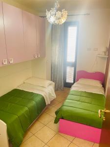 1 dormitorio con 2 camas con sábanas verdes y lámpara de araña en LA CASA DI NONNA GIOVANNA, en Fiumedinisi