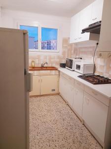 a kitchen with white cabinets and a white microwave at Appartement F3 avec balcon in Perpignan