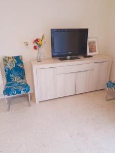 a living room with a tv and a chair at Appartement F3 avec balcon in Perpignan