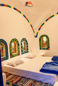 two beds in a room with colorful decorations on the wall at Nuba Narty in Aswan