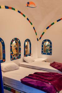two beds in a room with paintings on the wall at Nuba Narty in Aswan