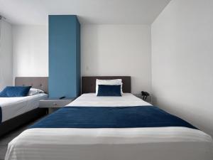 Hotel Rosales Gold في بيريرا: غرفة نوم بسريرين وجدار ازرق