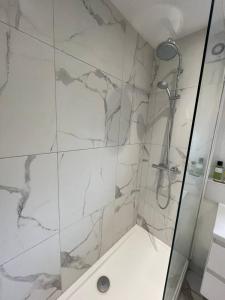 a bathroom with a shower with a marble wall at Contemporary 1BD Flat wBalcony - Stoke Newington! in London
