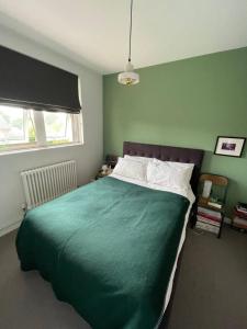 a green bedroom with a large bed with a green blanket at Contemporary 1BD Flat wBalcony - Stoke Newington! in London