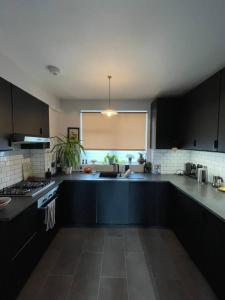 a kitchen with black cabinets and a sink and a window at Contemporary 1BD Flat wBalcony - Stoke Newington! in London