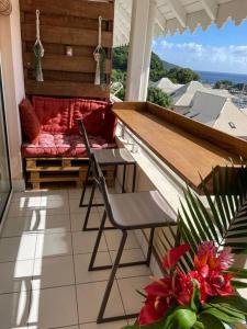 a balcony with a couch and a table and chairs at KARUK'IDîLE-Appartement Vue Mer - Plage à 200m in Gourbeyre