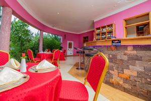 um restaurante com mesas e cadeiras vermelhas e um bar em Entuiga cottages em Hoima