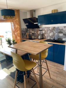 a kitchen with a wooden table and yellow chairs at KARUK'IDîLE-Appartement Vue Mer - Plage à 200m in Gourbeyre