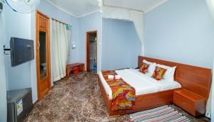 1 dormitorio con 1 cama y TV en Entuiga cottages en Hoima