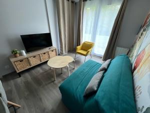 ein Wohnzimmer mit einem blauen Sofa und einem TV in der Unterkunft L’entrelacs in Équemauville