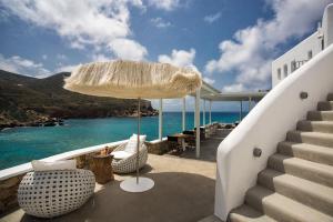 eine Terrasse mit Stühlen, einem Sonnenschirm und dem Meer in der Unterkunft Blue Sand Boutique Hotel & Suites in Agali