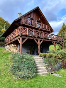 a large wooden house with stairs leading to it at SZUMiPOTOK Szczyrk in Szczyrk