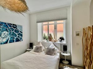 ein weißes Schlafzimmer mit einem Bett und einem Fenster in der Unterkunft Cocoma-Design-Apartment Deluxe - very central in München