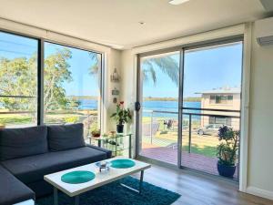 a living room with a couch and a large window at Cosy unit with park & water view in Ballina