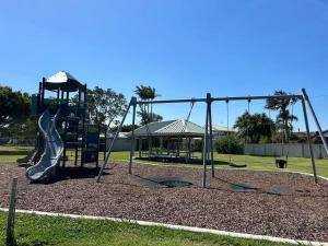 a playground with a slide in a park at Cosy unit with park & water view in Ballina