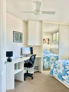 a bedroom with a desk with a computer and a bed at Cosy unit with park & water view in Ballina