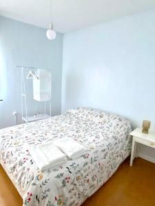 1 dormitorio con 1 cama con colcha blanca y flores en A casa do pai, en Pontevedra