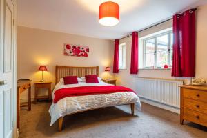 a bedroom with a bed with red curtains at The Crown Inn in Sarre
