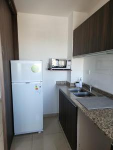 a kitchen with a white refrigerator and a sink at TORRE MAFALDA 15 Departamento nuevo con Pileta in Río Cuarto