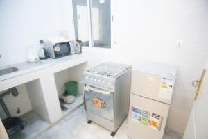 a kitchen with a stove and a sink and a refrigerator at Appartement entier F3 climatisé agréable, spacieux et confortable à Gadaye in Dakar