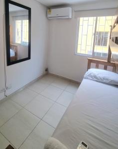 Habitación blanca con cama y espejo en Acogedor y Residencial piso 3 en Cartagena de Indias