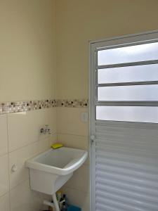 a white bathroom with a sink and a door at casa em Brotas 08 in Brotas