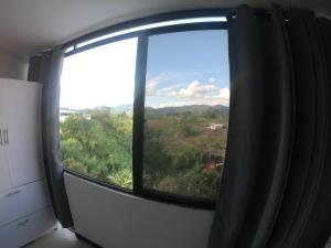una ventana en una habitación con vistas a los árboles en Apartaestudio en combia cerca aeropuerto PEI, en Pereira