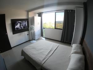 1 dormitorio con cama y ventana grande en Apartaestudio en combia cerca aeropuerto PEI, en Pereira