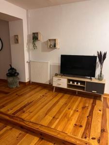 ein Wohnzimmer mit einem Flachbild-TV auf einem Holzboden in der Unterkunft Le chalet percheron in La Loupe