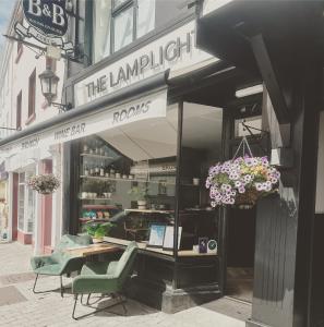 a store front with a table and chairs in a street at Lamp Light Rooms in Clifden
