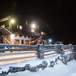 uma casa com uma cerca na neve à noite em Berggasthof Biberg em Saalfelden am Steinernen Meer