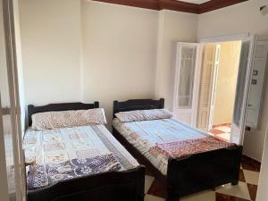 2 Betten in einem Zimmer mit Tür in der Unterkunft شقق فندقيه برج شيفورليه حي الدولار in Marsa Matruh
