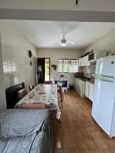 a kitchen with a long table and a refrigerator at Casa para alugar em Bertioga - Piscina, Wifi e Churrasqueira in Bertioga