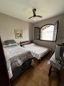 a bedroom with two beds and a ceiling fan at Casa para alugar em Bertioga - Piscina, Wifi e Churrasqueira in Bertioga