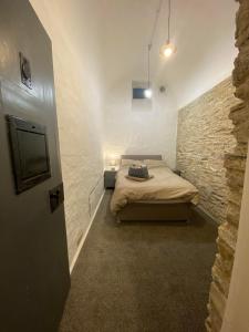 1 dormitorio con cama y pared de piedra en Victorian Police Station Apartment en Launceston