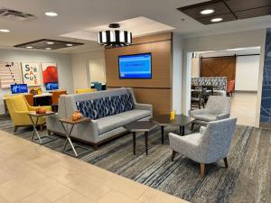 a lobby with a couch and chairs in a waiting room at Holiday Inn Express & Suites Dewitt - Syracuse, an IHG Hotel in East Syracuse