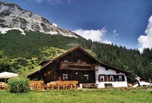 a building with tables and chairs in front of a mountain at Ferienwohnung Waldfrieden in Absam