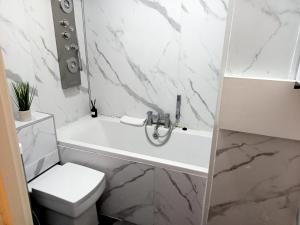 a white bathroom with a tub and a toilet at Studio apartment in London, Bethnal Green in London