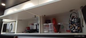 a white kitchen shelf with a kitchen utensils and auggage at Apto 5 Estrelas no Centro de Pelotas in Pelotas