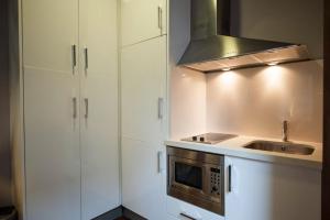 a kitchen with white cabinets and a sink and a stove at MyHouseSpain - Apartamentos Moros 41 in Gijón