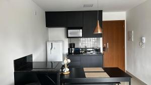 a kitchen with black cabinets and a black counter top at Apartamento mobiliado a 500m do Goiânia Shopping in Goiânia