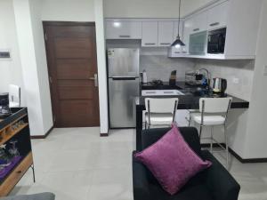 a kitchen with a couch with a purple pillow at Departamento Familiar en Equipetrol in Santa Cruz de la Sierra